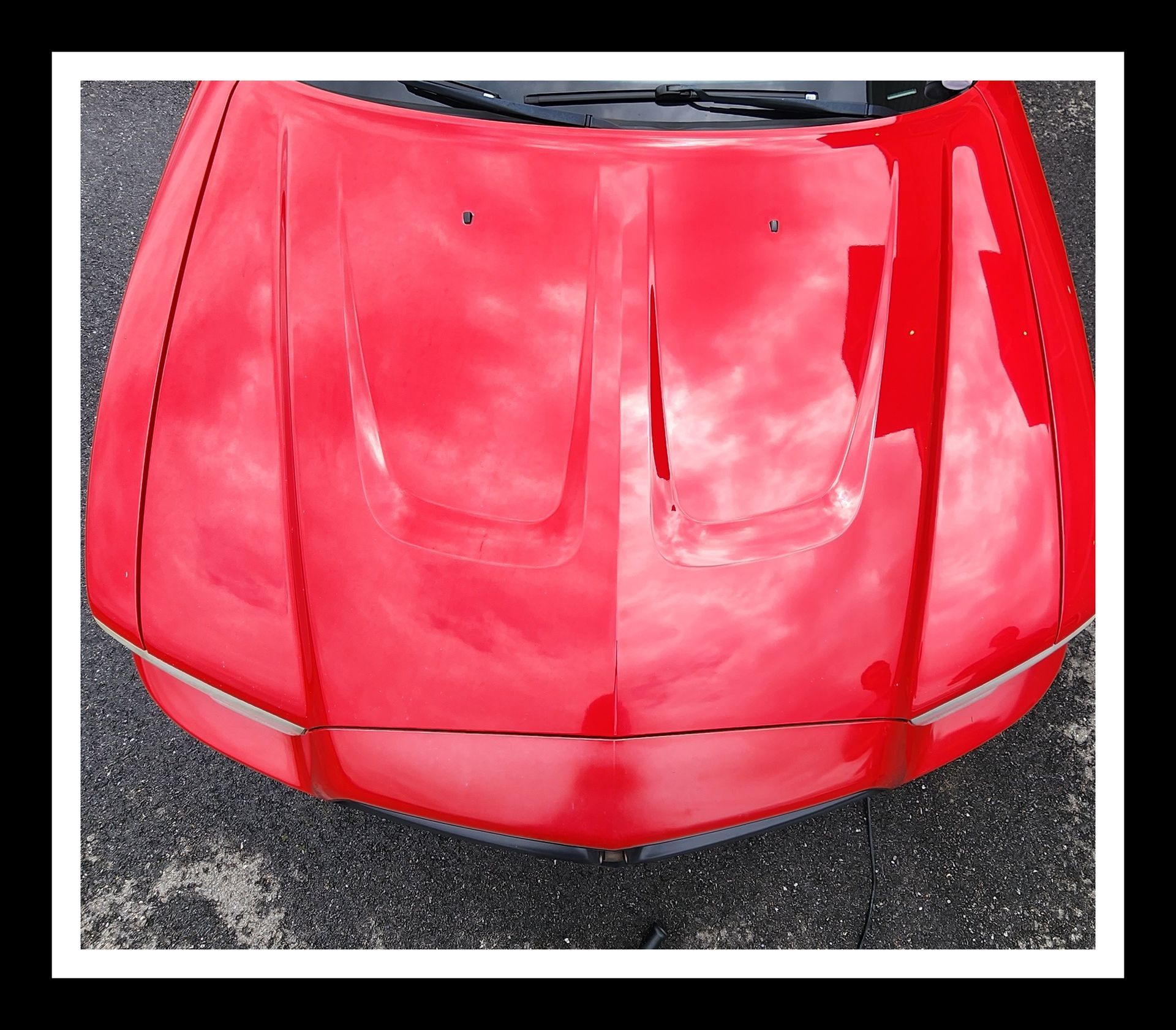 The hood of a red car is shown from above