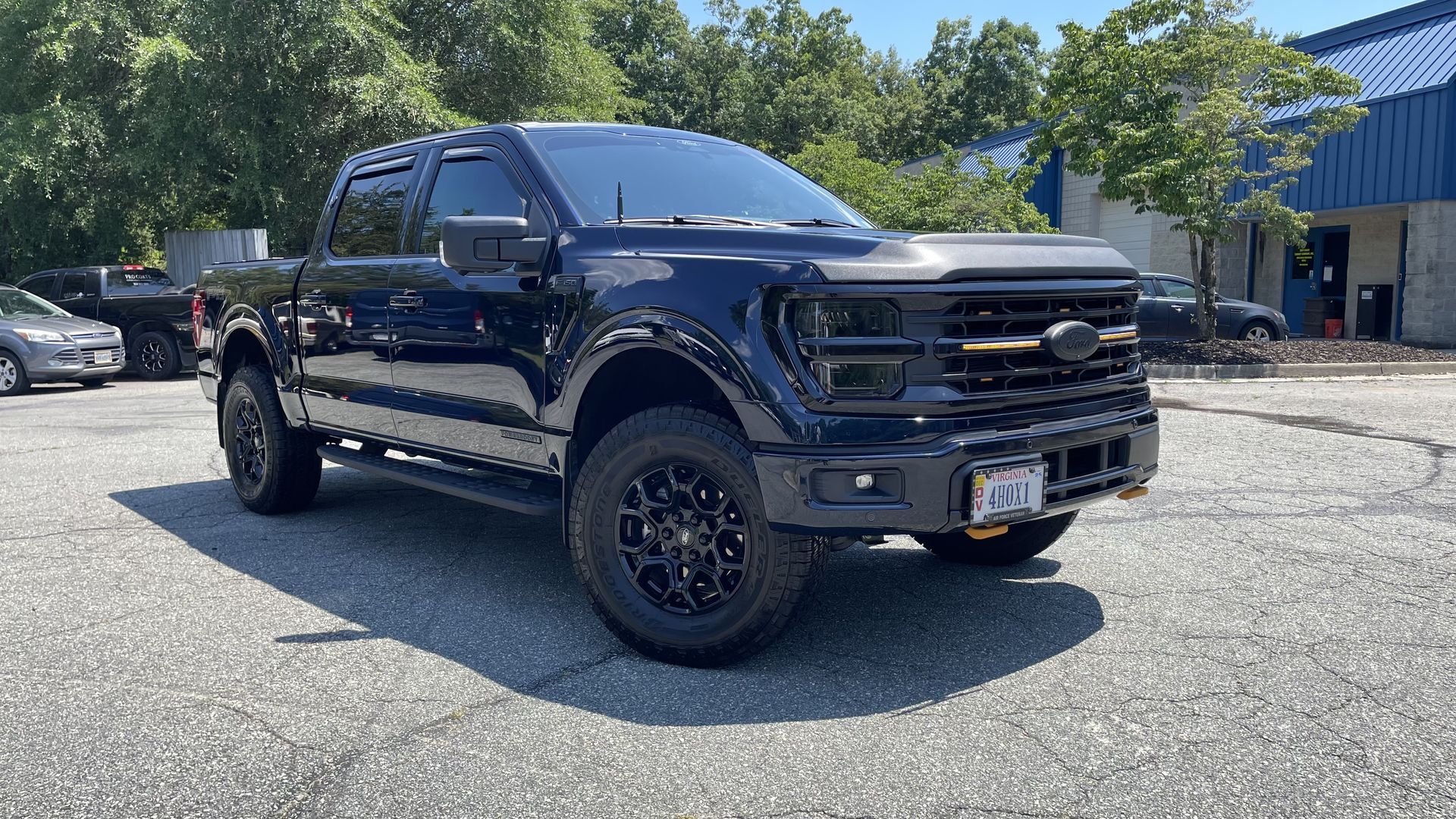 Dark blue Ford pickup truck parked in a parking lot on a sunny day.
