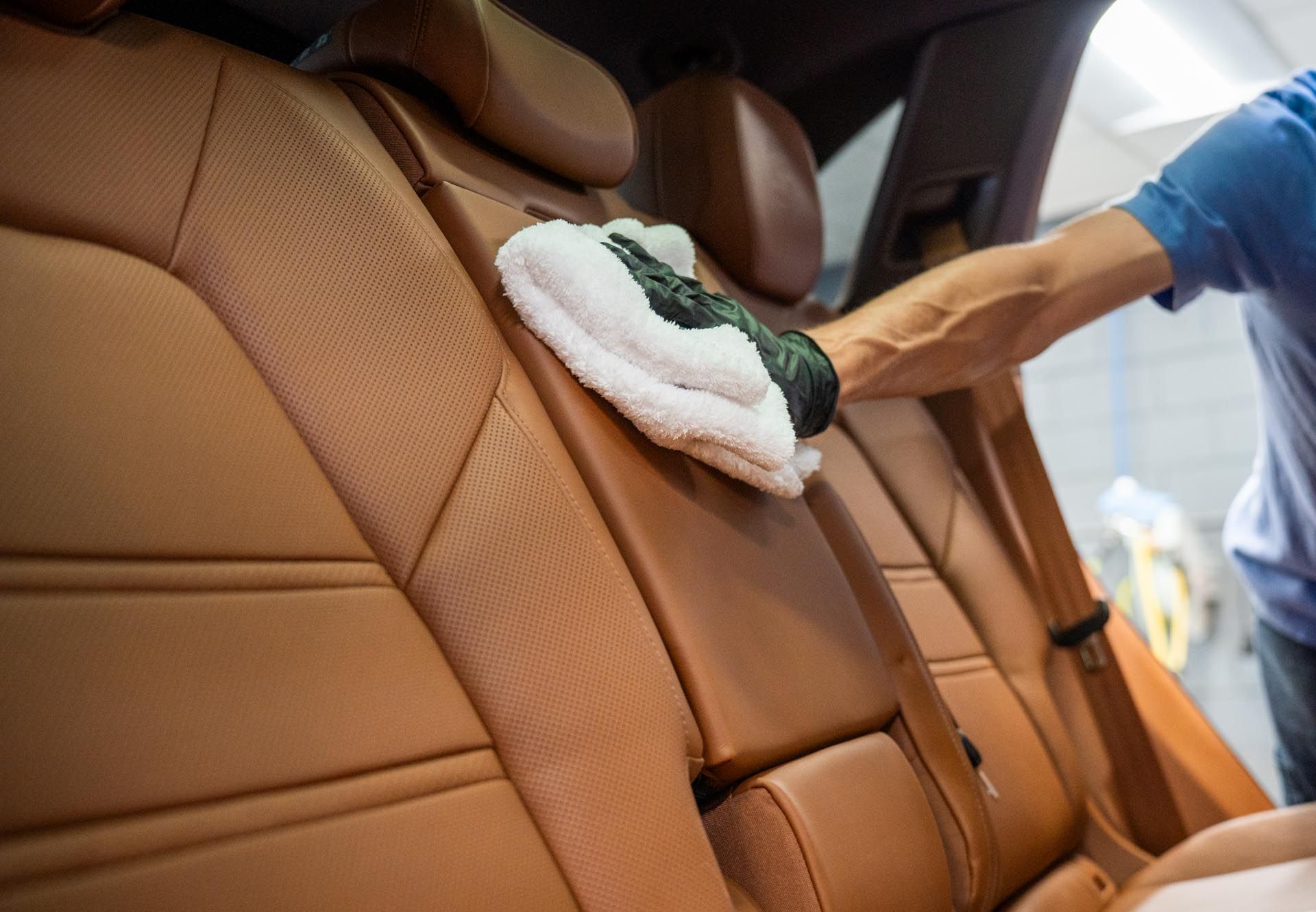 A man is cleaning the back seat of a car with a towel .