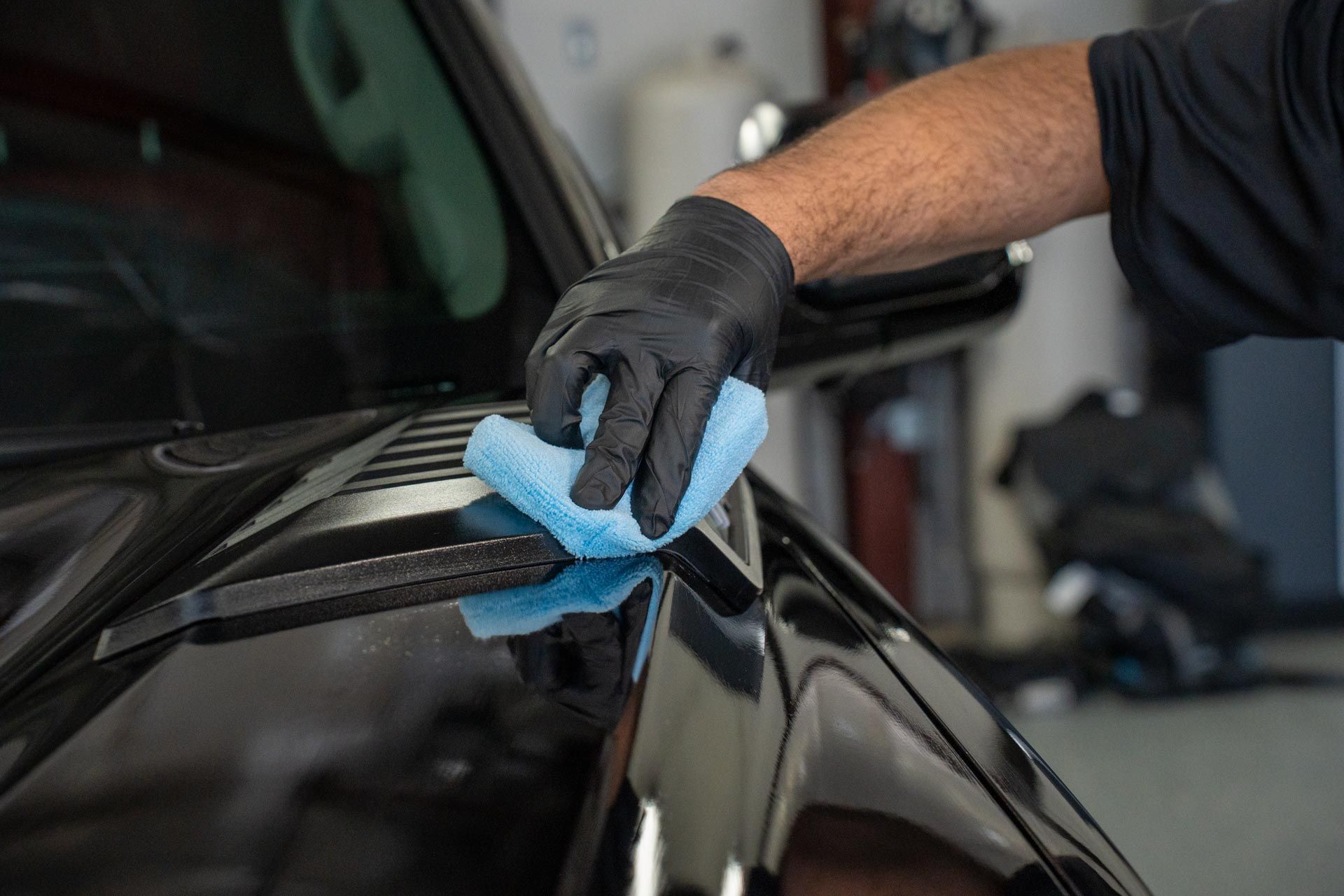 a man is cleaning a black car with a blue cloth .