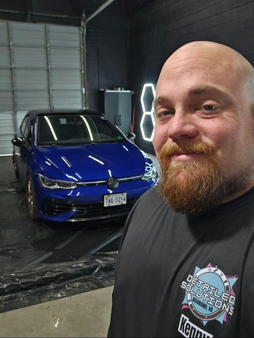 a man is cleaning the hood of a red sports car with a towel .