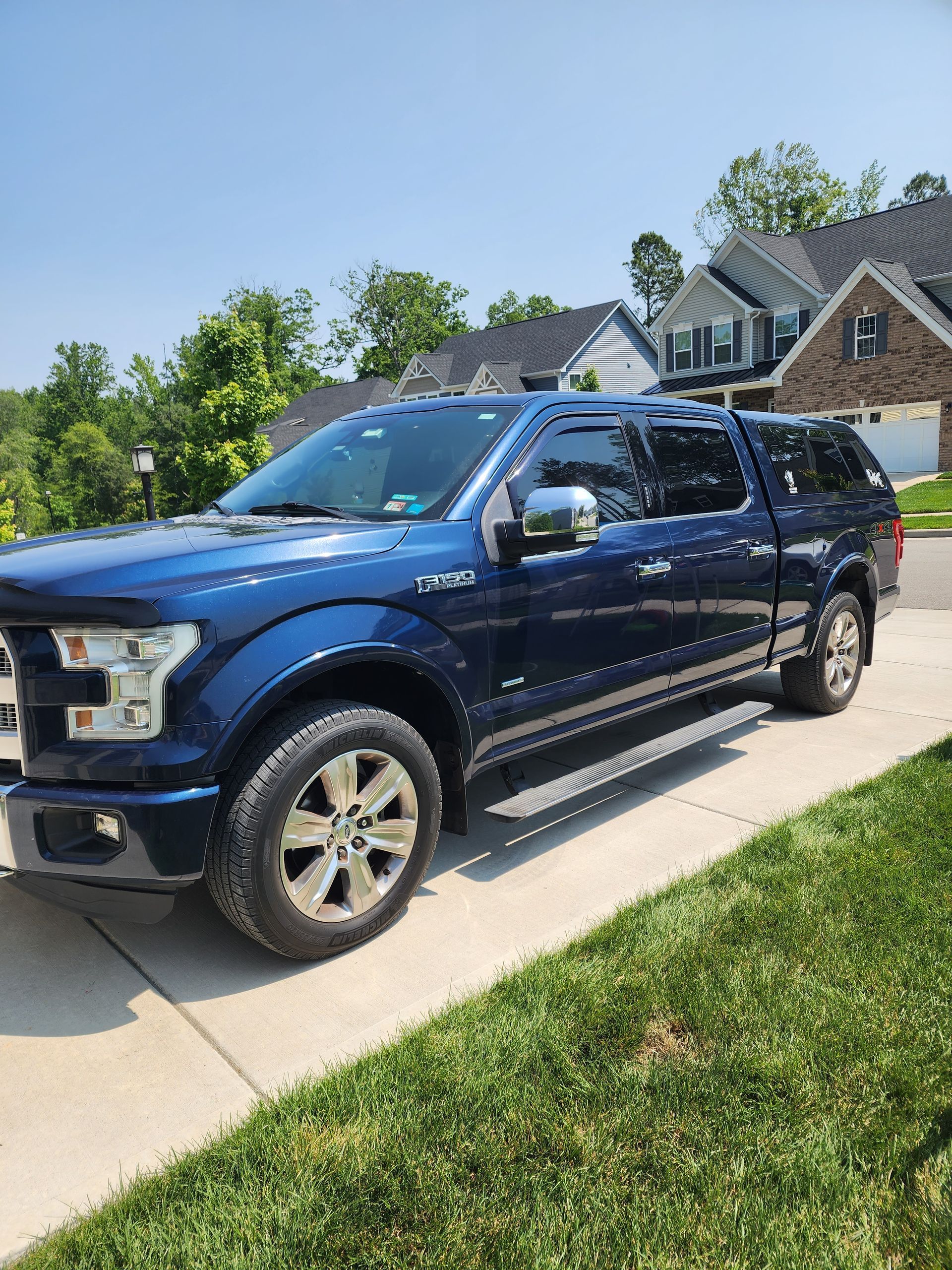 Blue pickup truck parked in a suburban driveway under a sunny sky