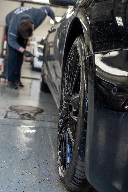 A man is washing a black car in a garage .
