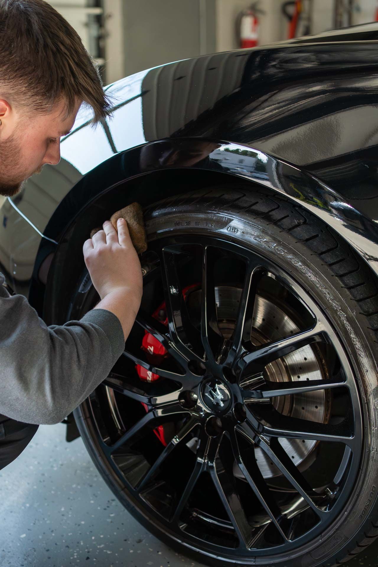 a man is cleaning the fender of a black car with a brush .