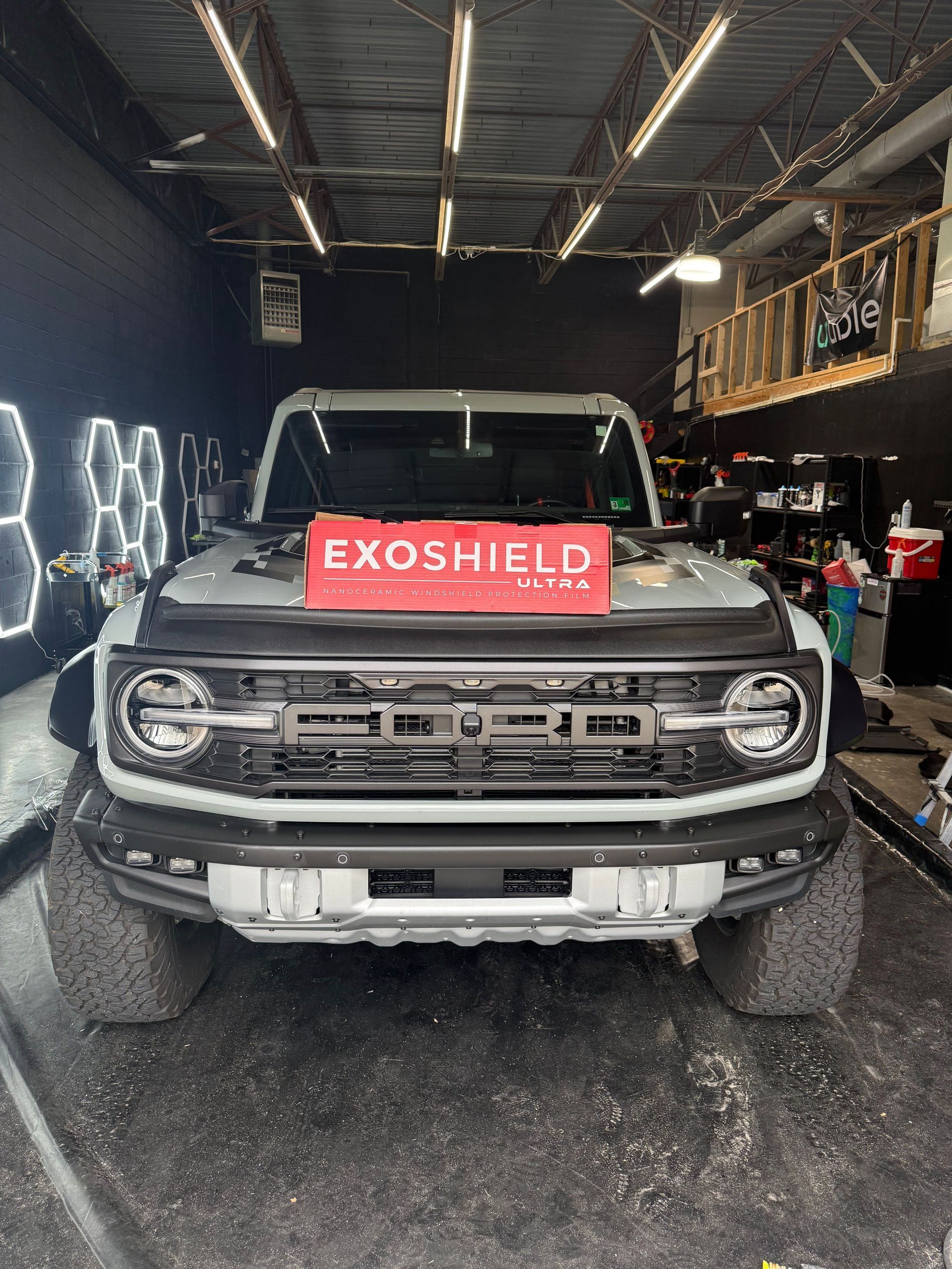 Gray Ford Bronco with Exoshield sign in a garage.