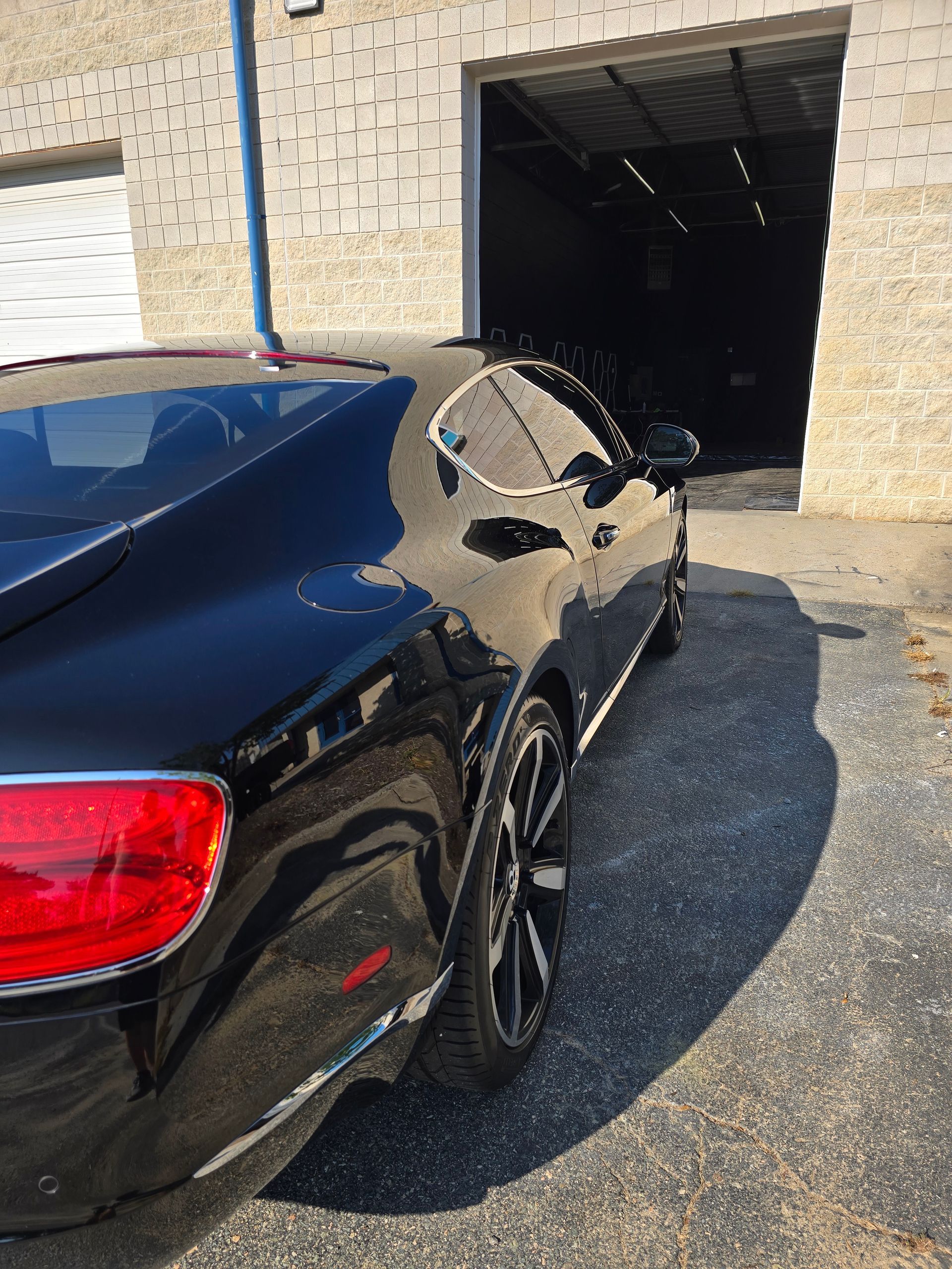 Black Bentley coupe parked outside a garage.