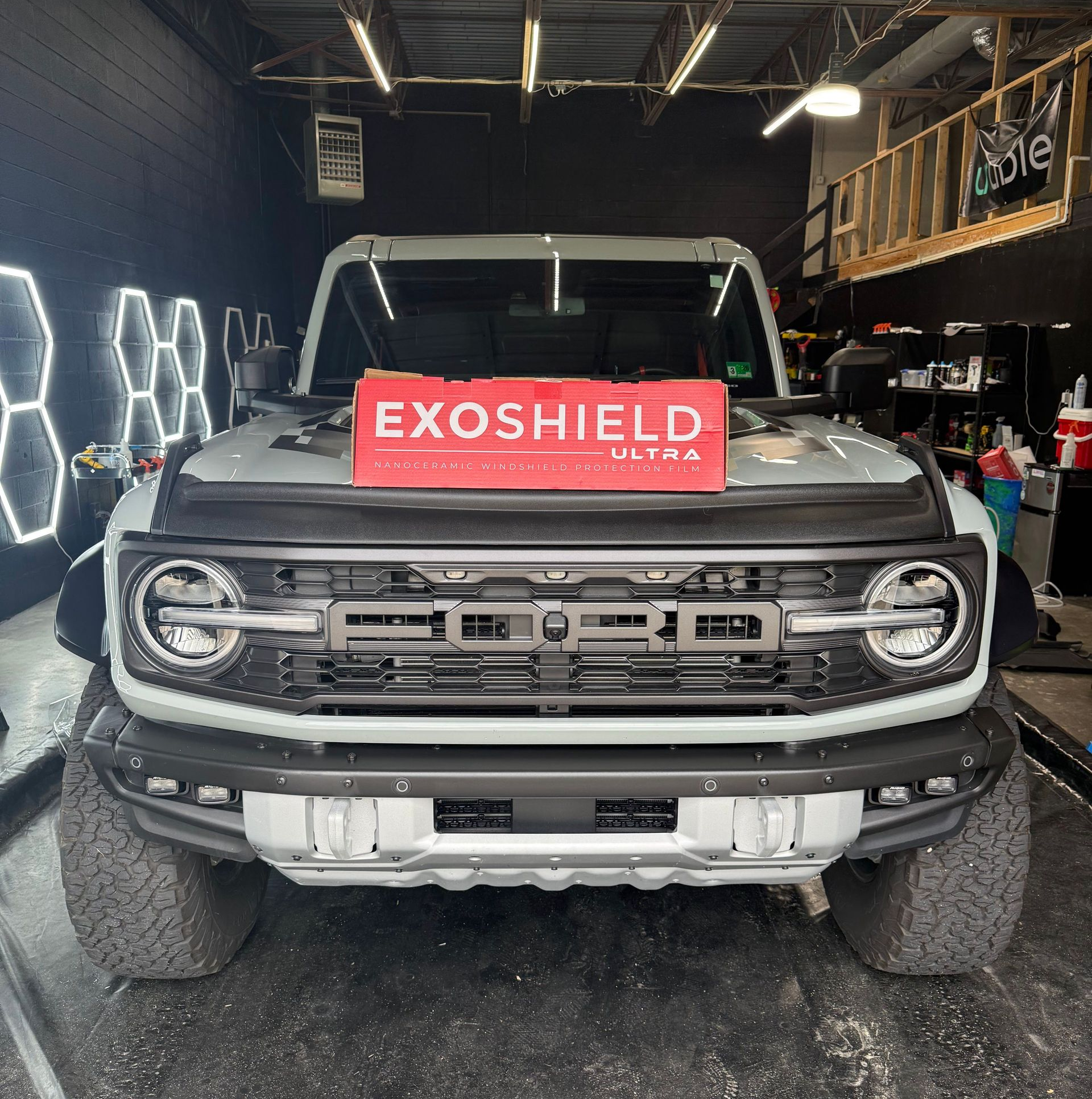 A light-colored Ford Bronco with a red 