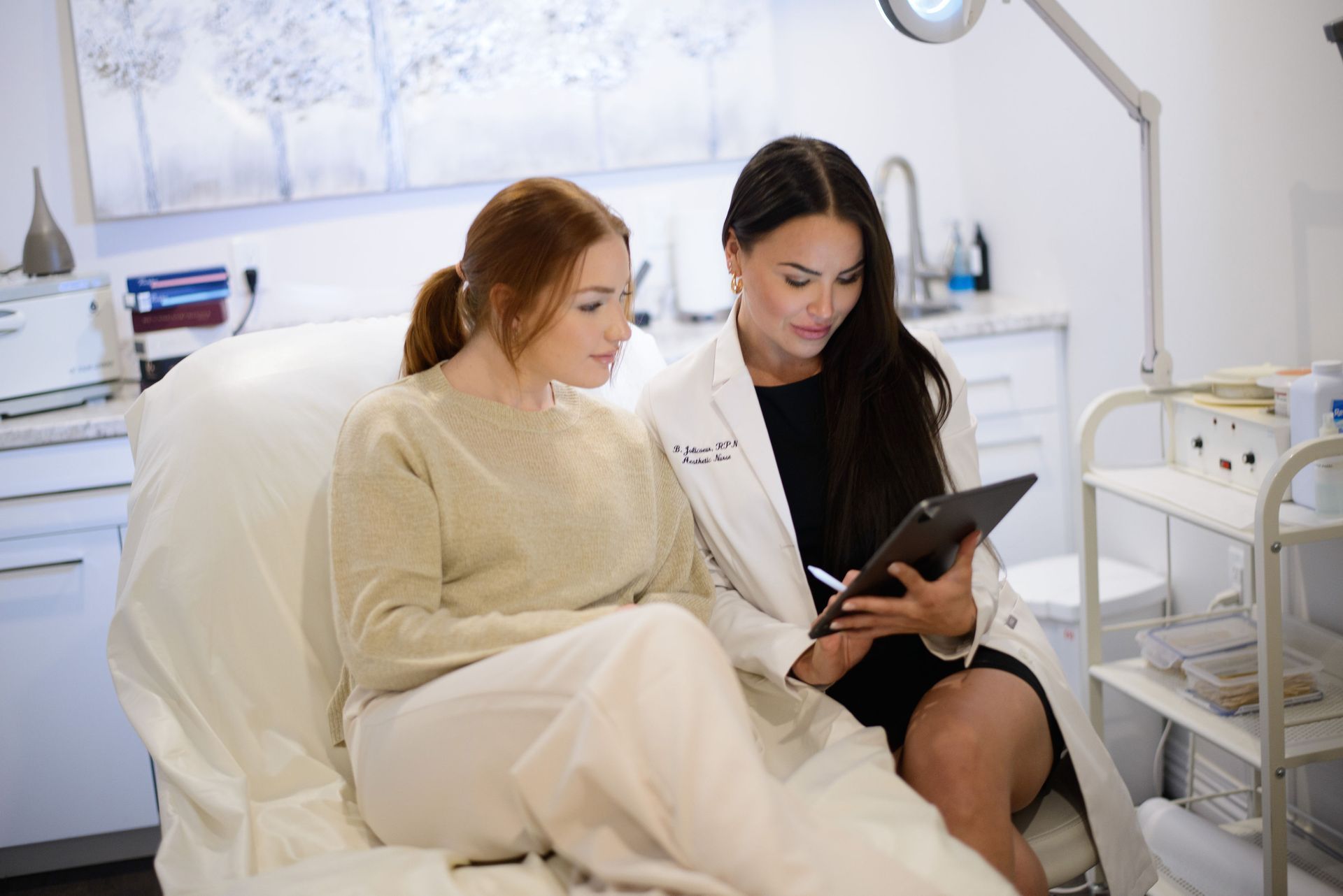 A woman wearing a straw hat and a denim jacket is touching her hair.