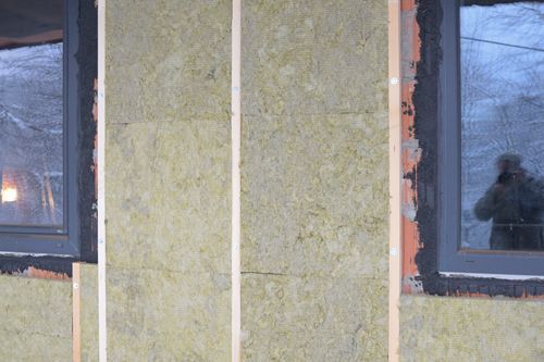 Insulation panels with wood framing installed on a building exterior, near a window.