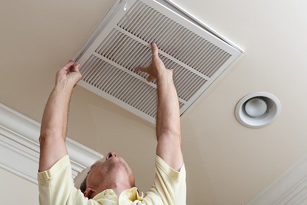 man replacing ventilation cover in ceiling