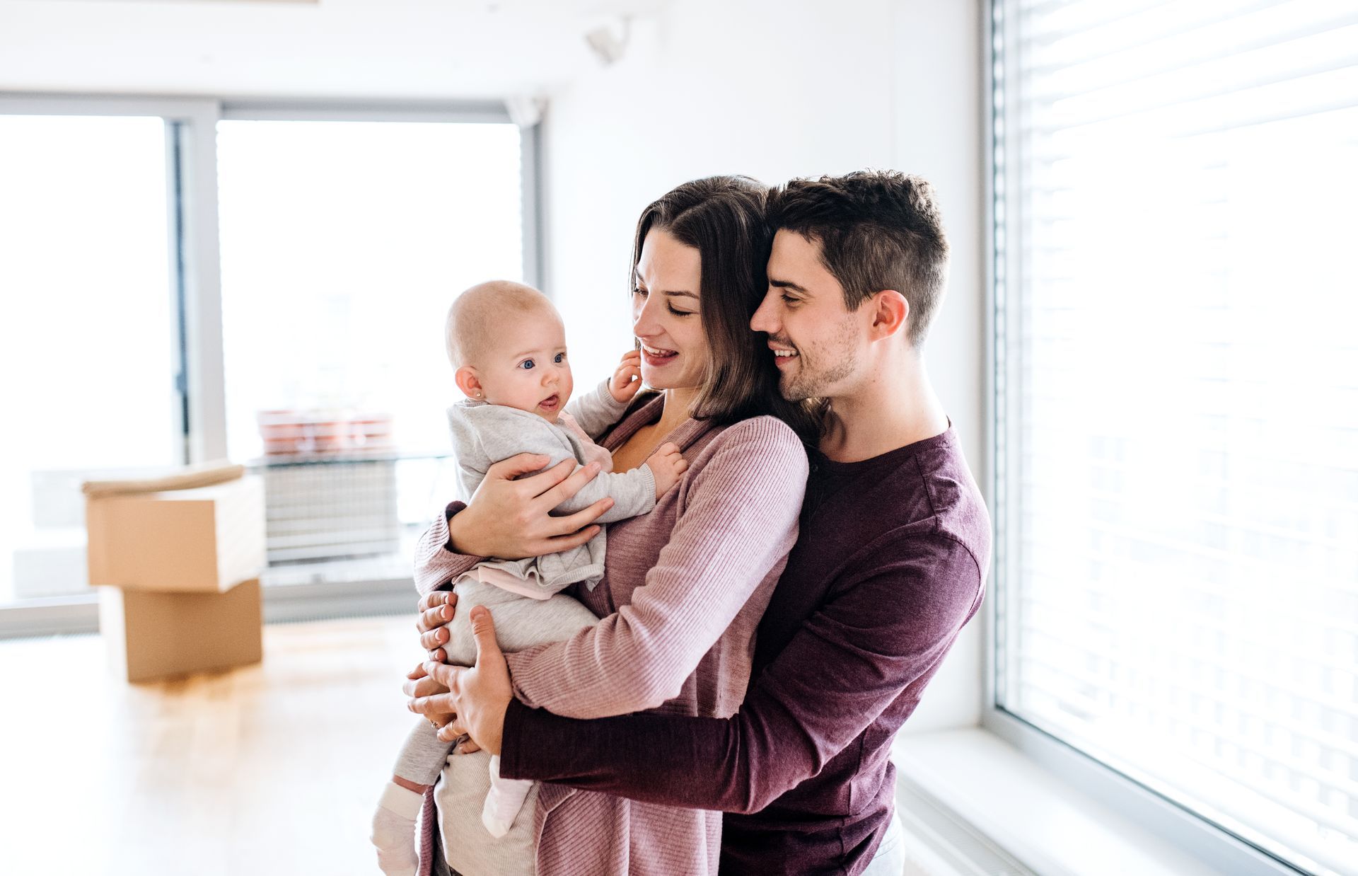 A man and woman are holding a baby in their new home.