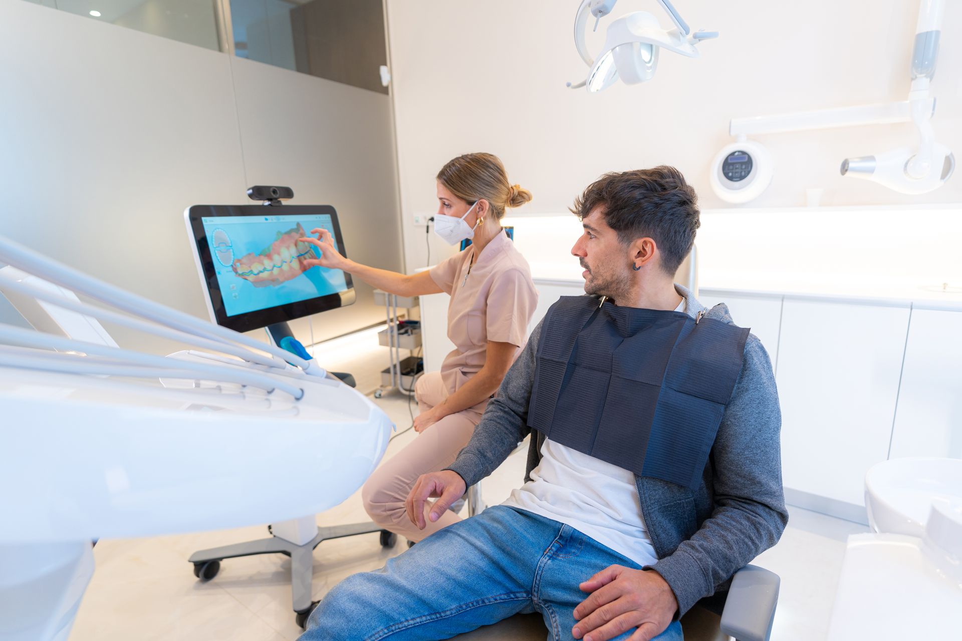 A man is sitting in a dental chair looking at a computer screen.
