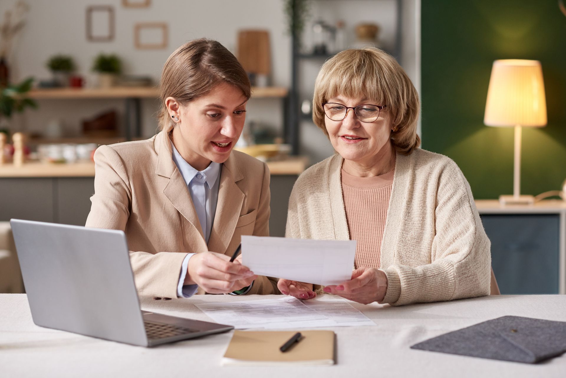 Two women are sitting at a table looking at a piece of paper.