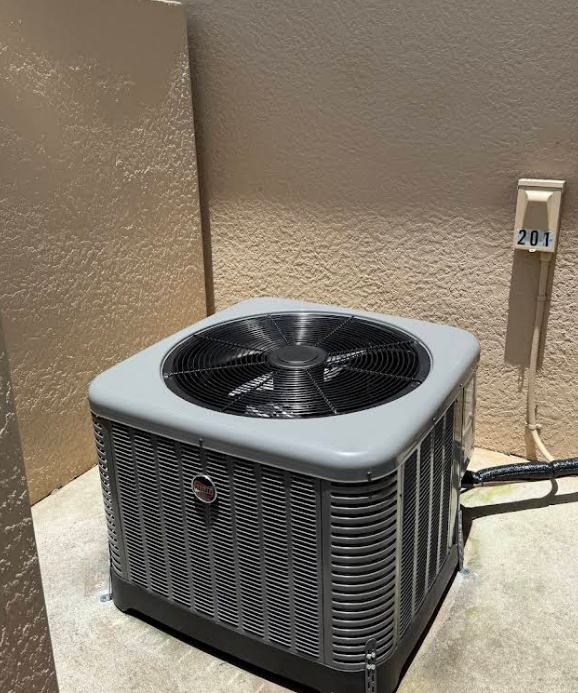 Gray air conditioner unit in a beige alcove, with a unit number 201 on the wall.