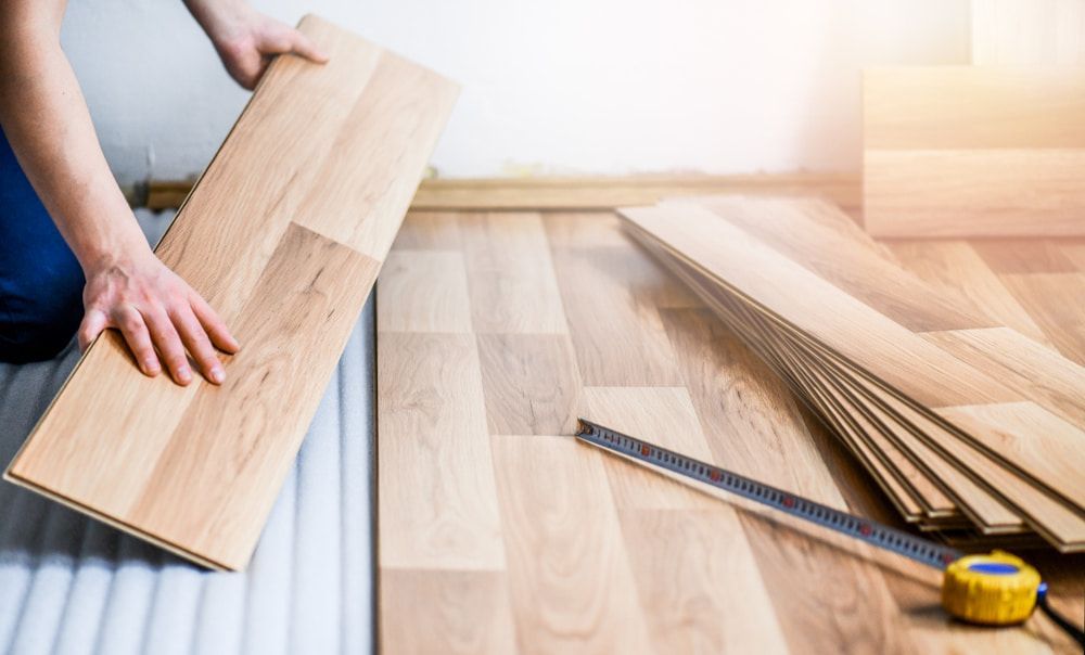 A Person Is Installing a Wooden Floor in A Room — Lismore Floor Sanding in Casino, NSW