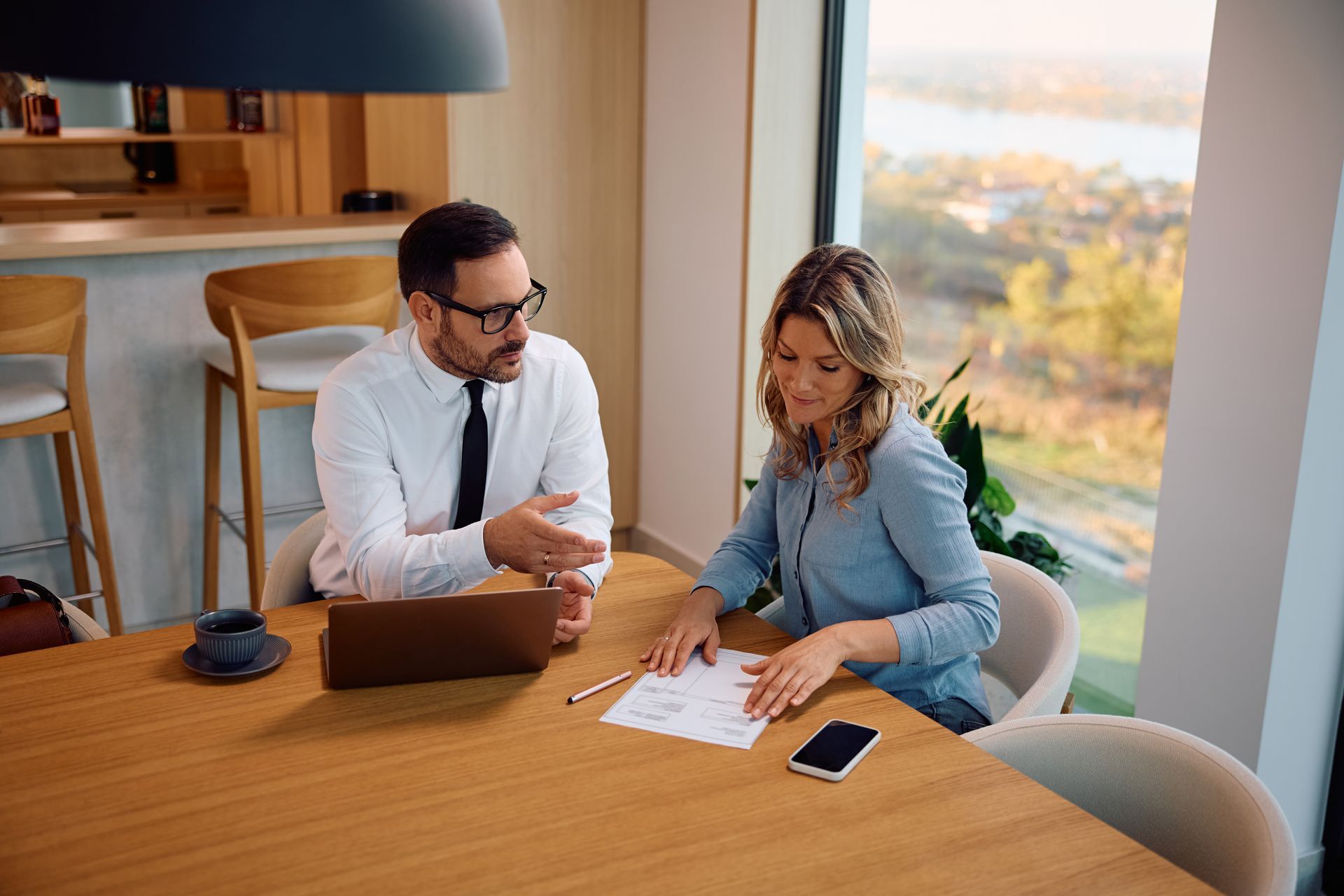 Man in orange shirt gestures, talking to another man with arm around him on a couch.