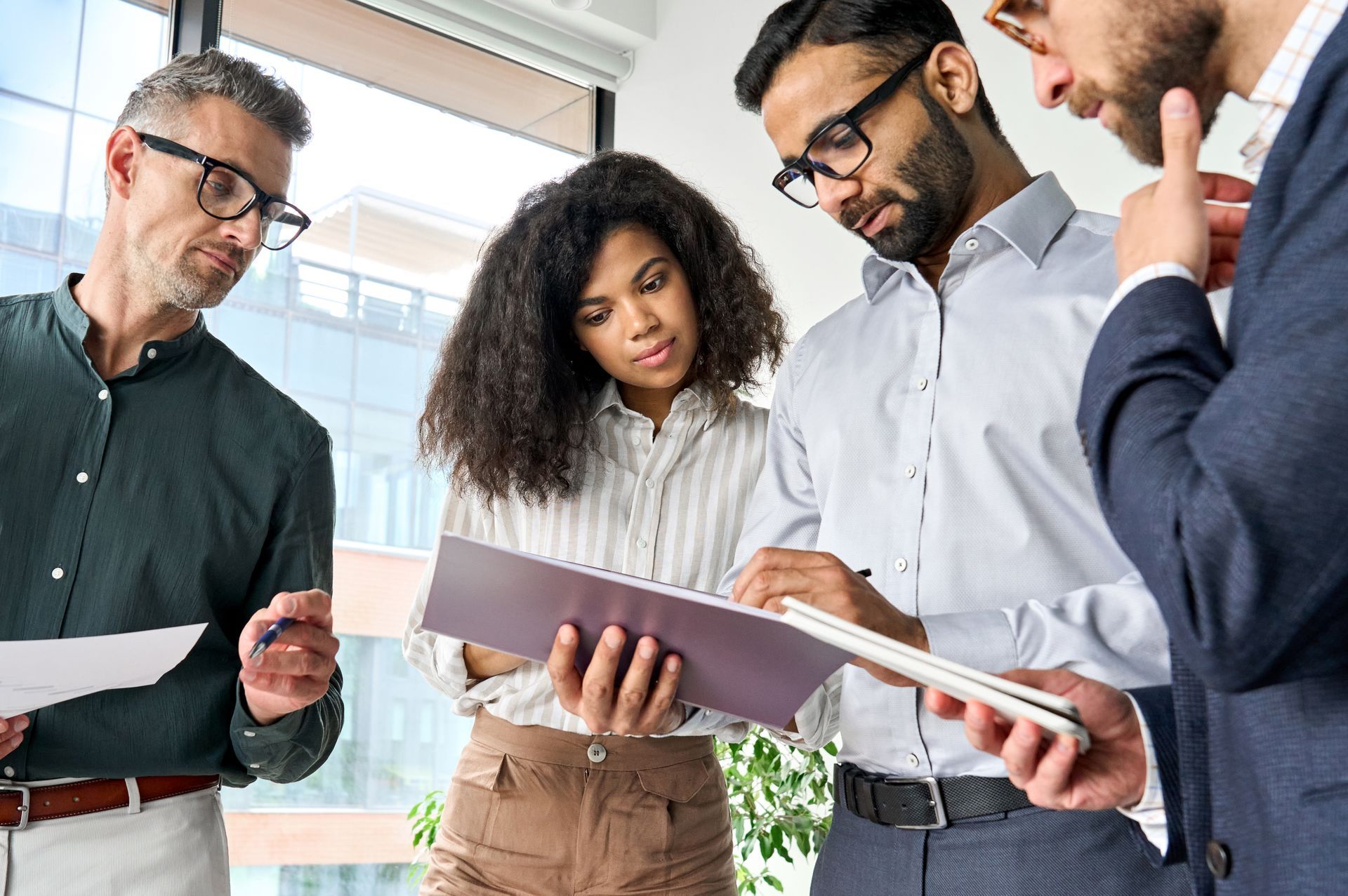 Man in orange shirt gestures, talking to another man with arm around him on a couch.