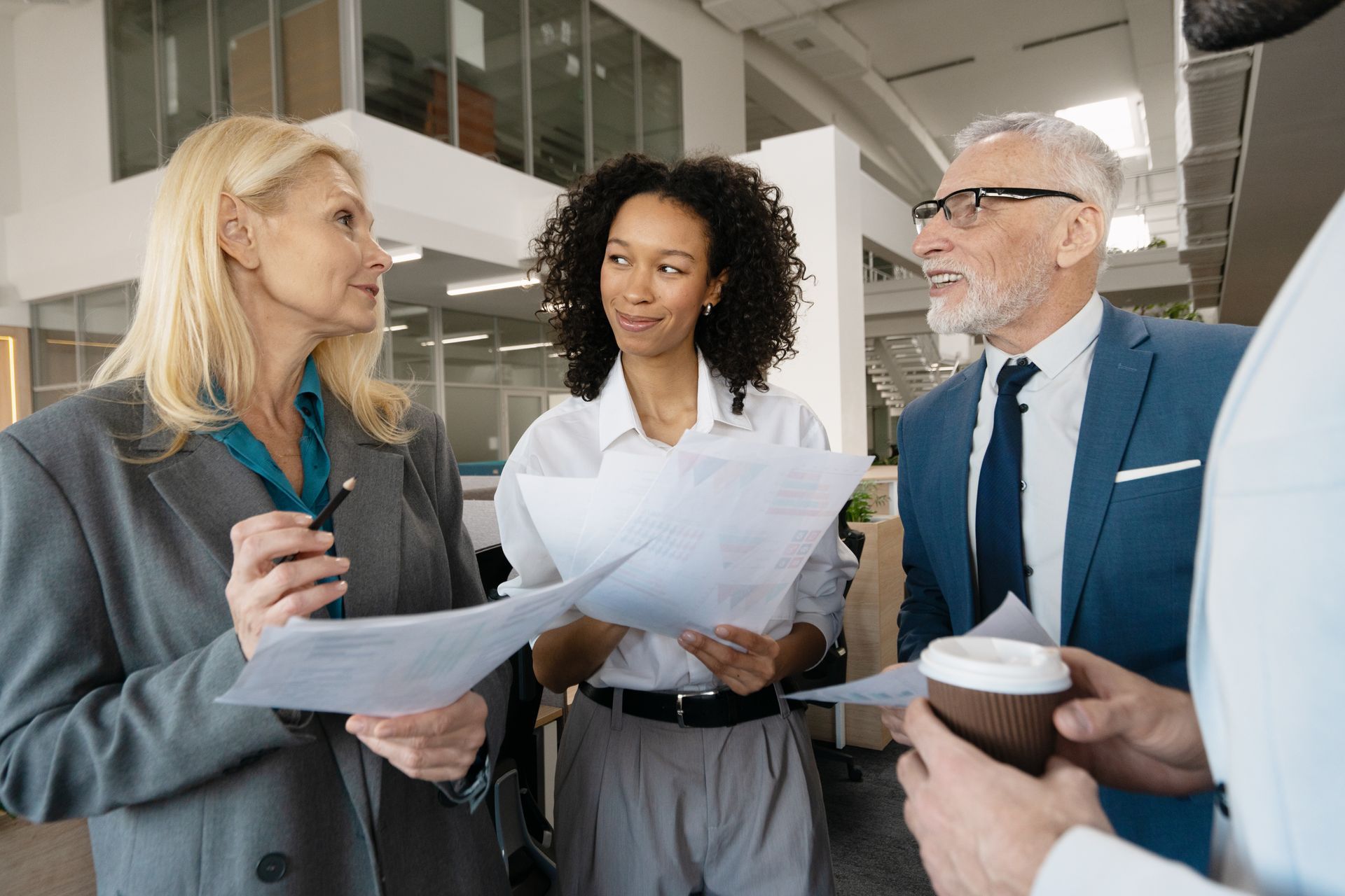 Family reads together on a couch, a girl smiles at a book. Others watch: grandparents and an older girl.