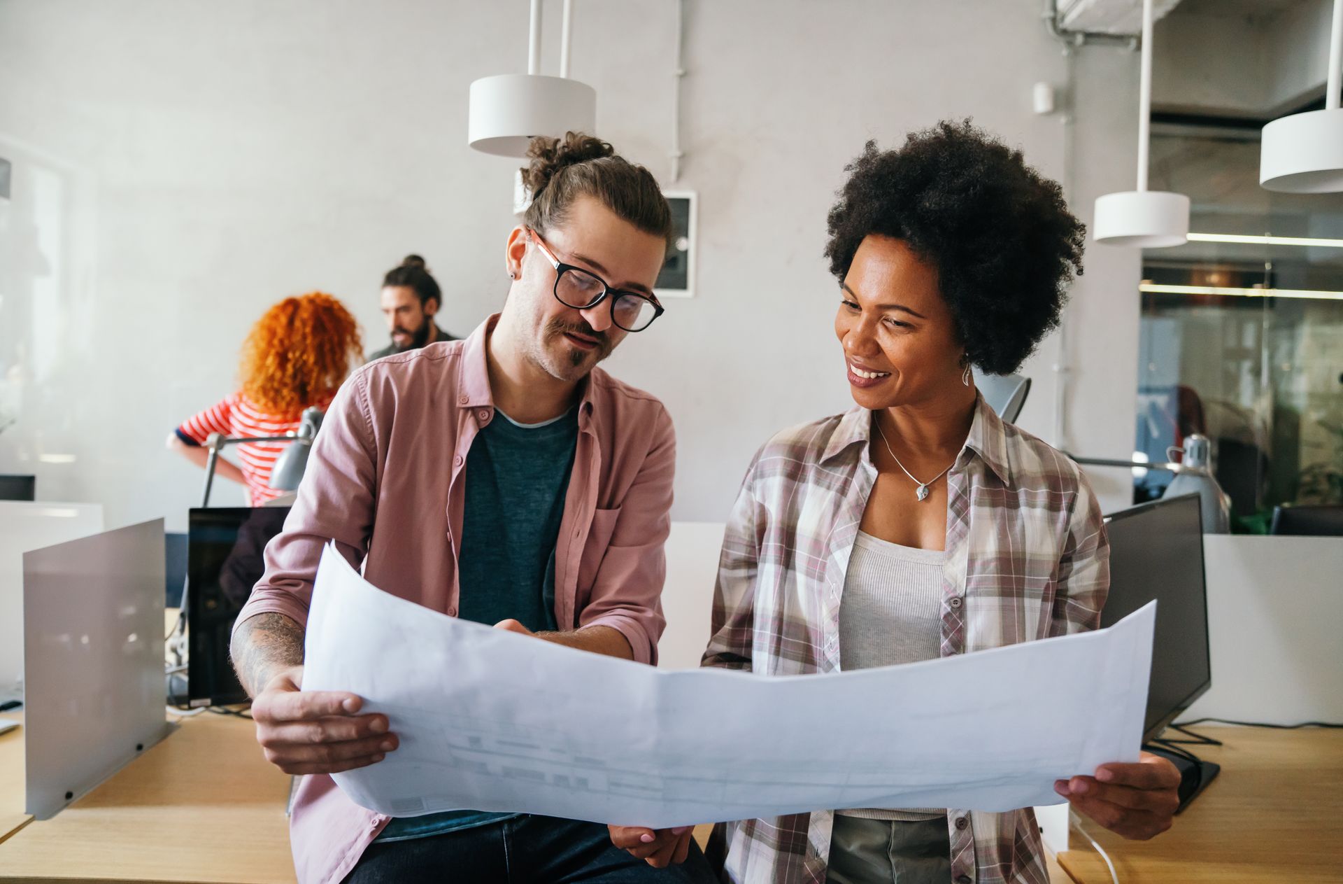 Family reads together on a couch, a girl smiles at a book. Others watch: grandparents and an older girl.