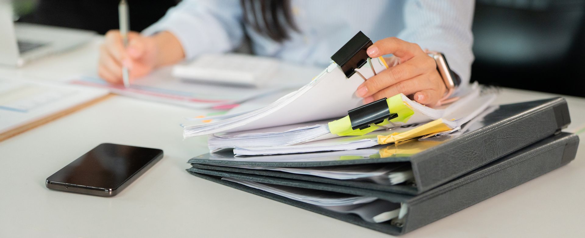 Man in orange shirt gestures, talking to another man with arm around him on a couch.
