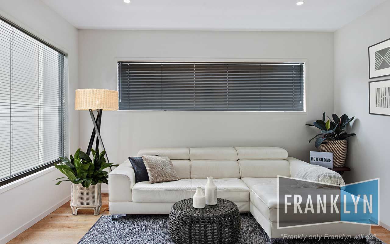 Living Room With White Couch, Dark Blinds, Potted Plants, and Woven Coffee Table — Seaview Blinds & Shutters in Rockhampton, QLD