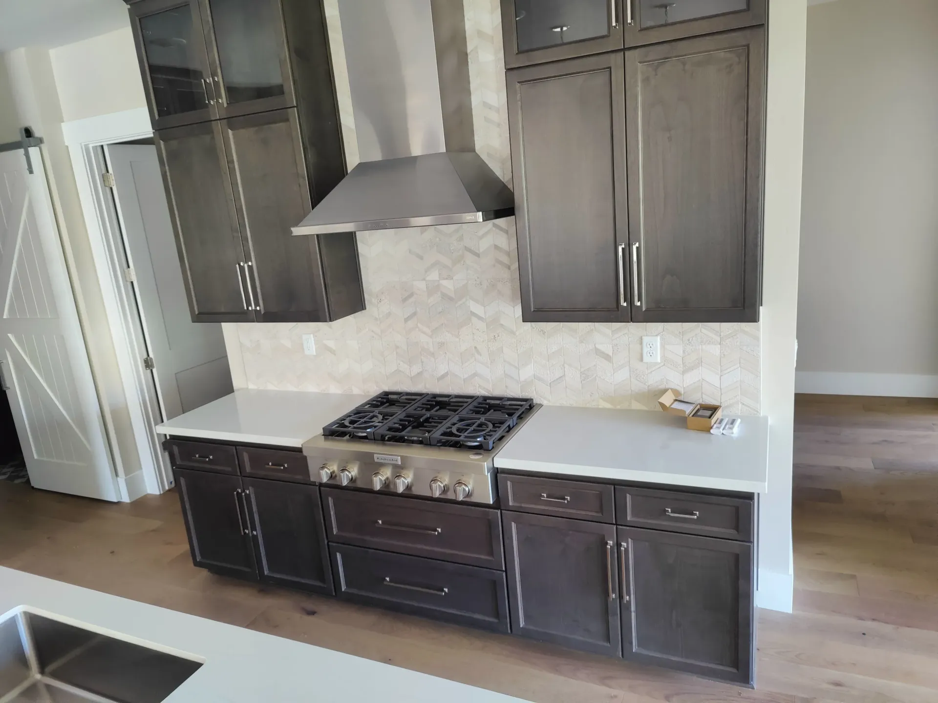Kitchen with dark gray cabinets, white countertops, stainless steel range and hood.