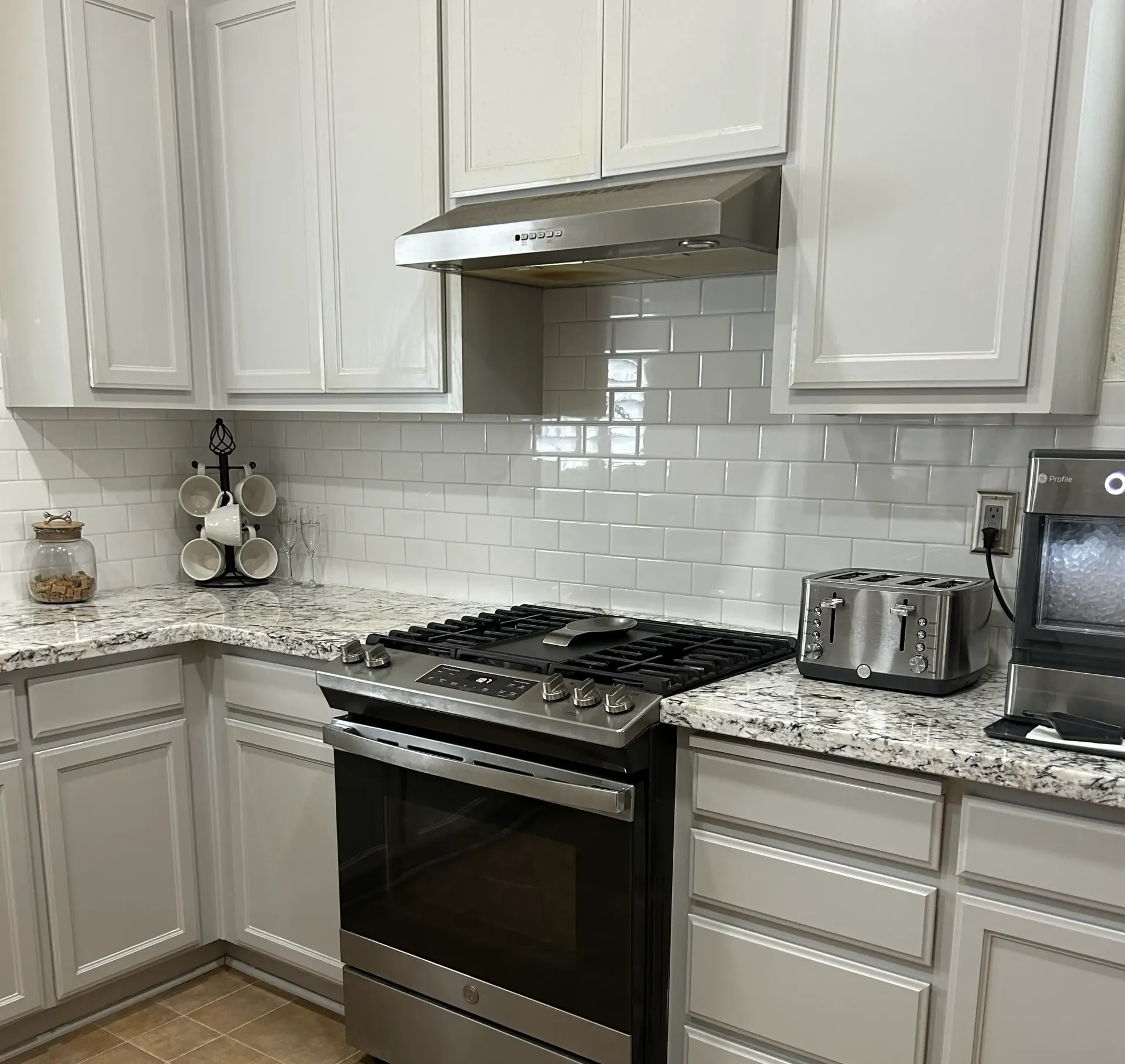 A modern kitchen with white cabinets, a stainless steel oven, and a white subway tile backsplash.