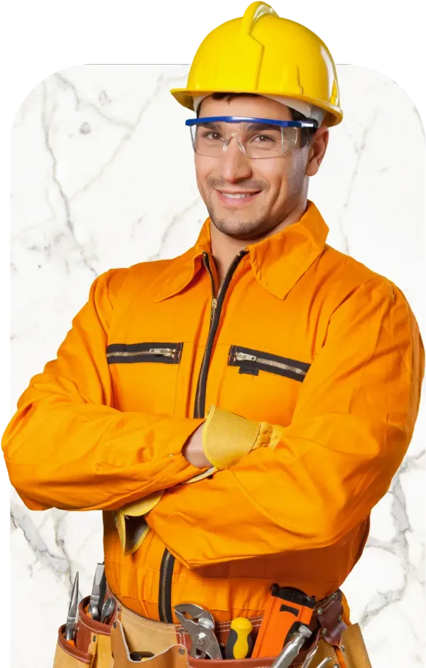 Construction worker in orange coveralls, yellow hard hat, and safety glasses, smiling with arms crossed.