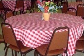 a table with a red and white checkered tablecloth and a vase of flowers on it .