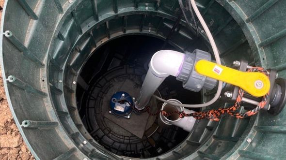 Rover arm inside a metal cylindrical chamber, seen from above, with cables and equipment attached.