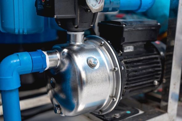 Blue pipes connected to a stainless steel pump and black motor in an industrial setting