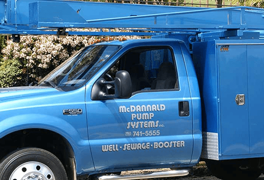 Blue McDonald Pump Systems service truck with ladder rack and utility box parked outdoors