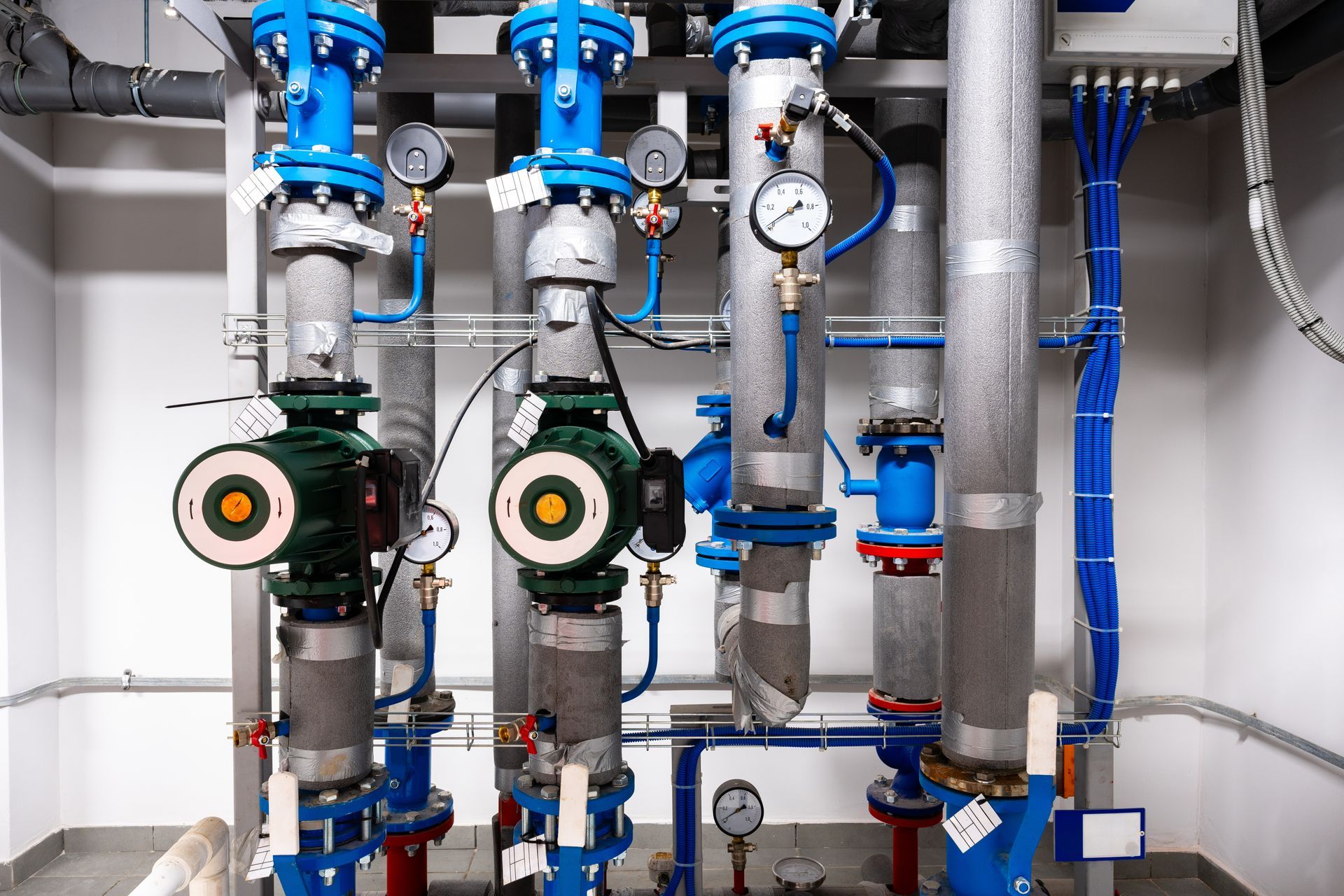 Industrial pipes and valves with gauges in a utility room.