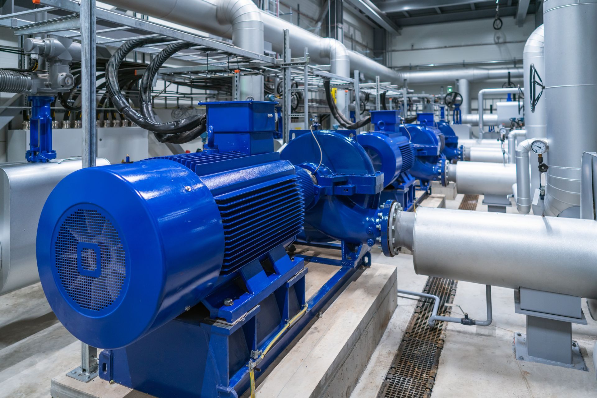 Blue industrial pumps and pipes in a mechanical room