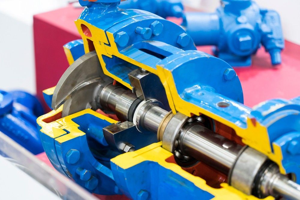 Worker adjusting valves on industrial pipes beside a blue pump and pressure gauge