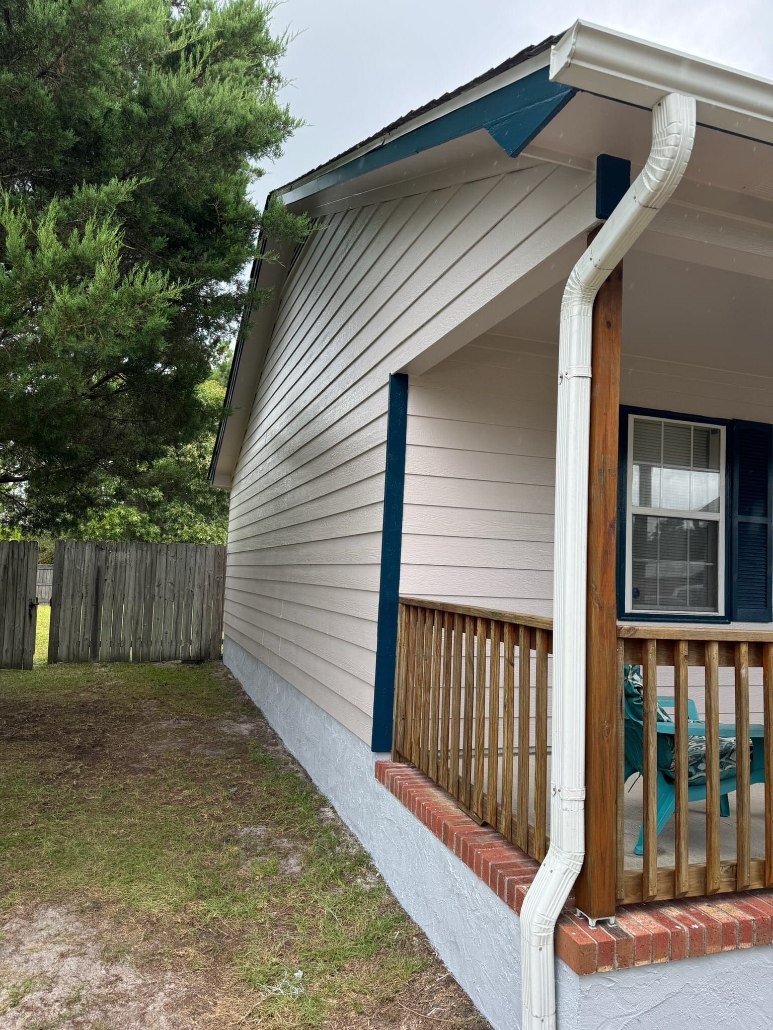 A mobile home with a porch and a gutter on the side of it.