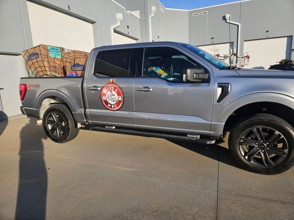 A gray truck with boxes in the back is parked in front of a building.