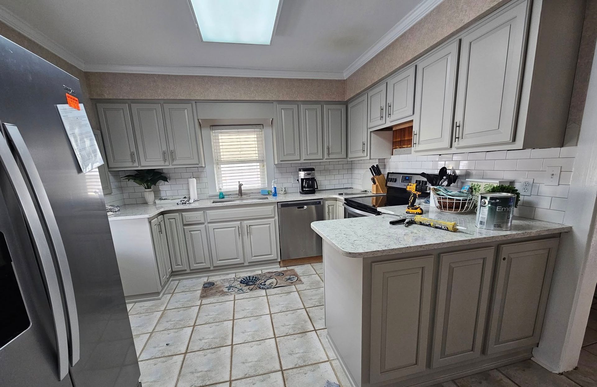 A kitchen with white cabinets , stainless steel appliances , granite counter tops and a refrigerator.