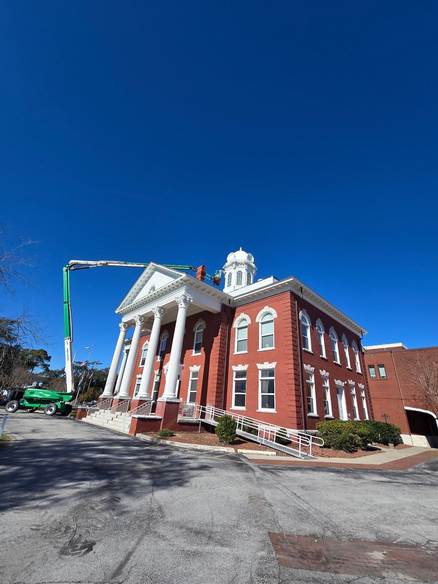 A large red brick building with a green crane on top of it.