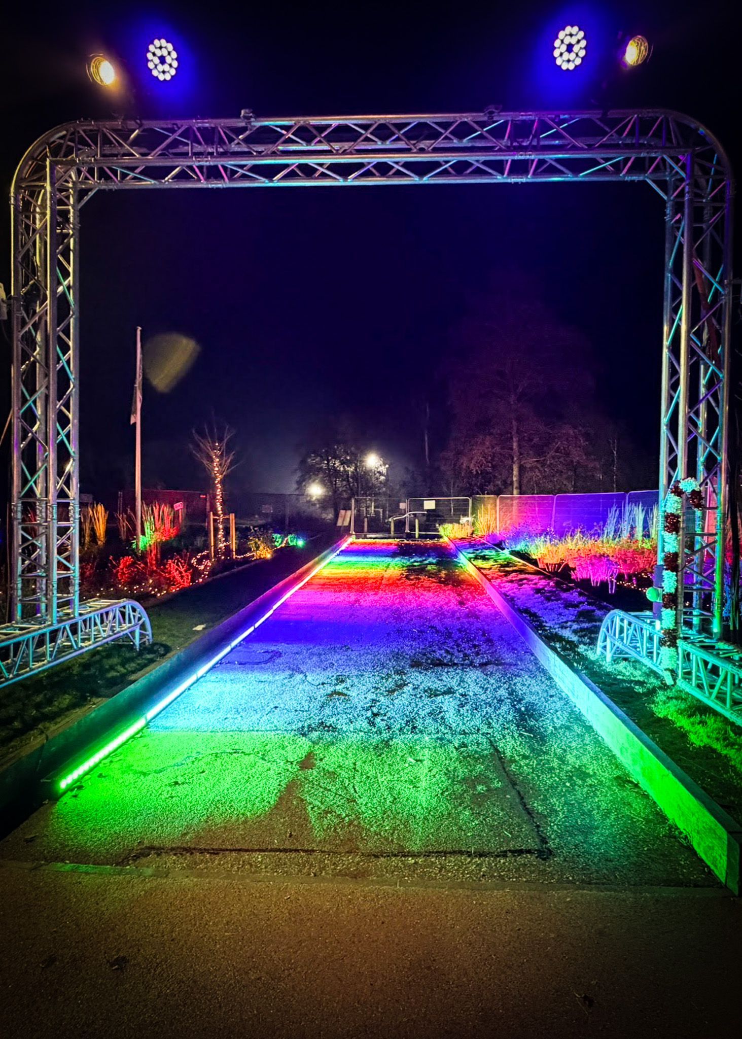 Pathway at a Christmas light event lit with a multicoloured effect scrolling from one end to the other.