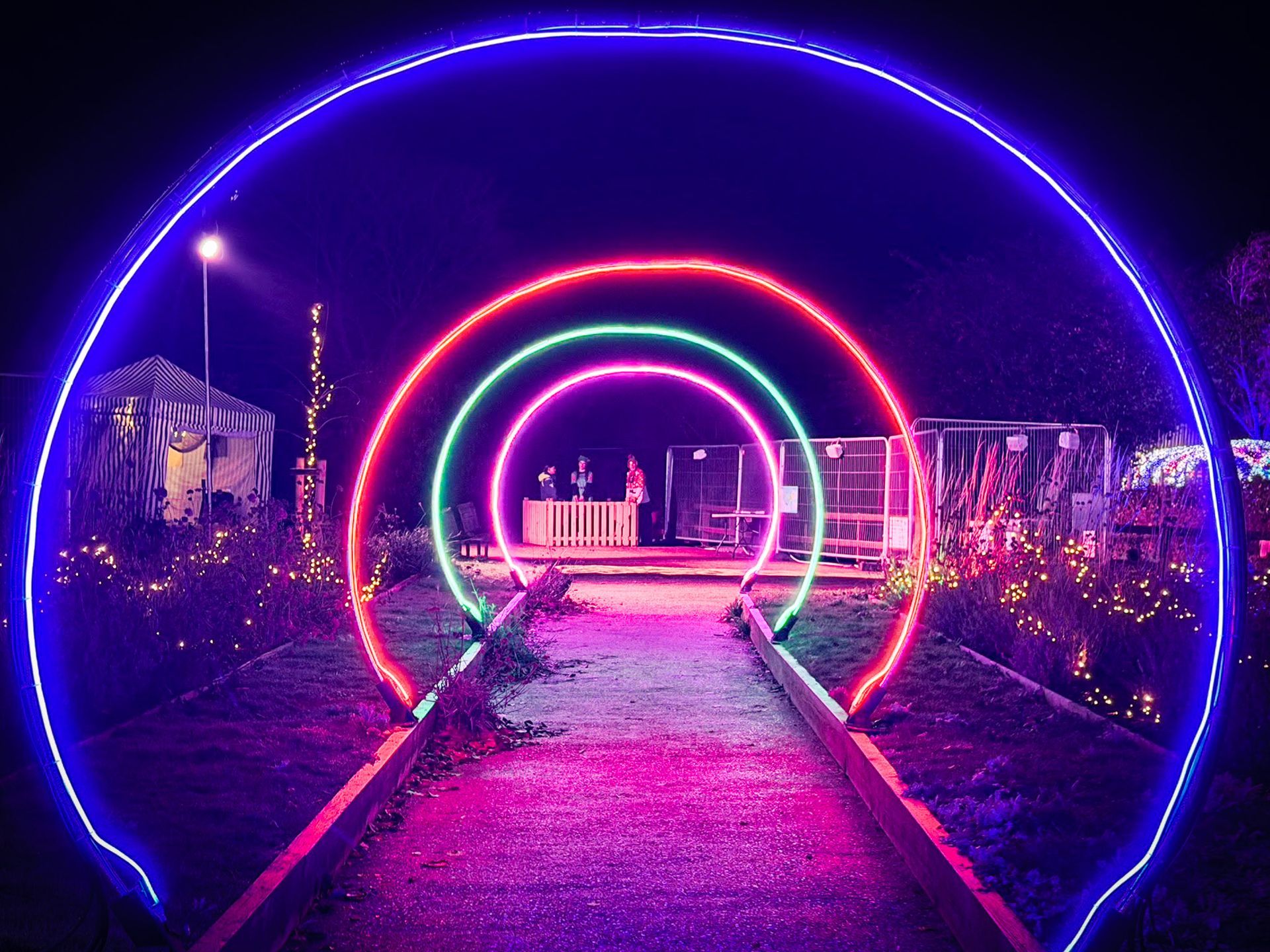 A tunnel of light up neon arches at a christmas light trail event.