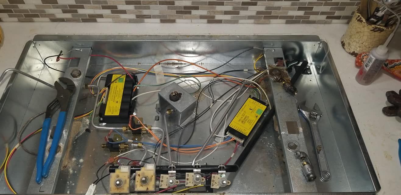 The inside of a stove with a lot of wires coming out of it.