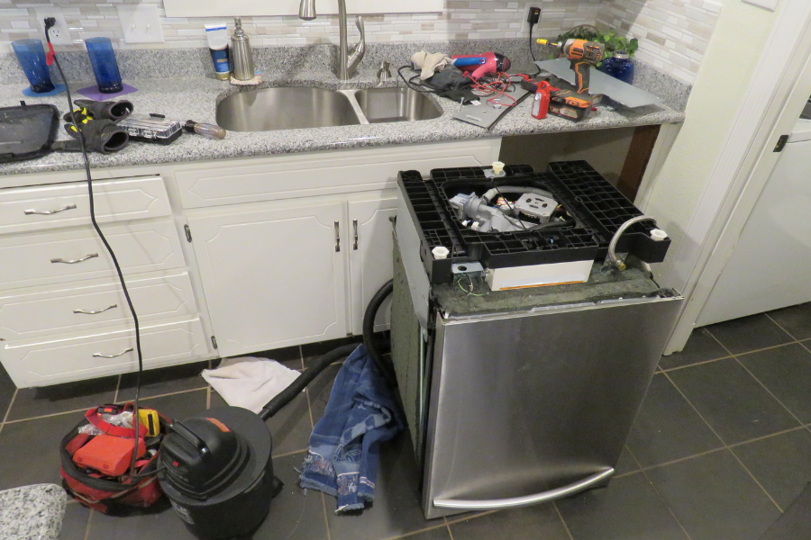 A stainless steel dishwasher is being installed in a kitchen.