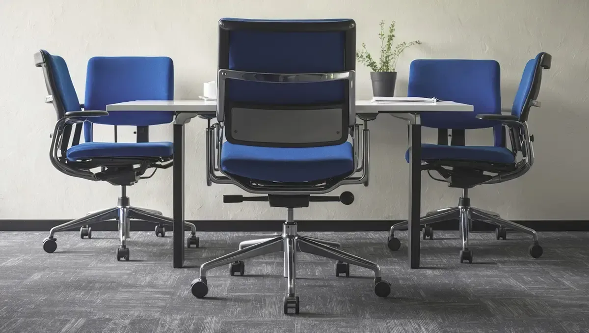 Een conferentieruimte met blauwe stoelen en een tafel.