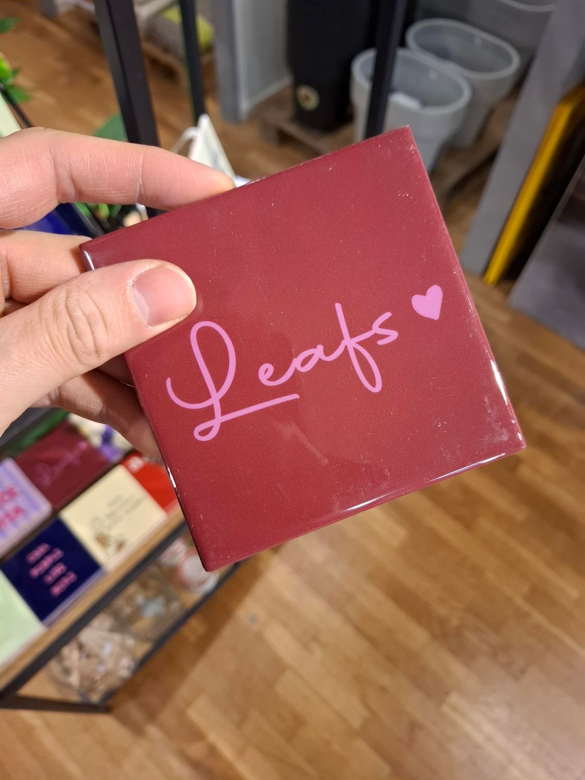 Hand die een bordeauxrode vierkante doos met het opschrift 