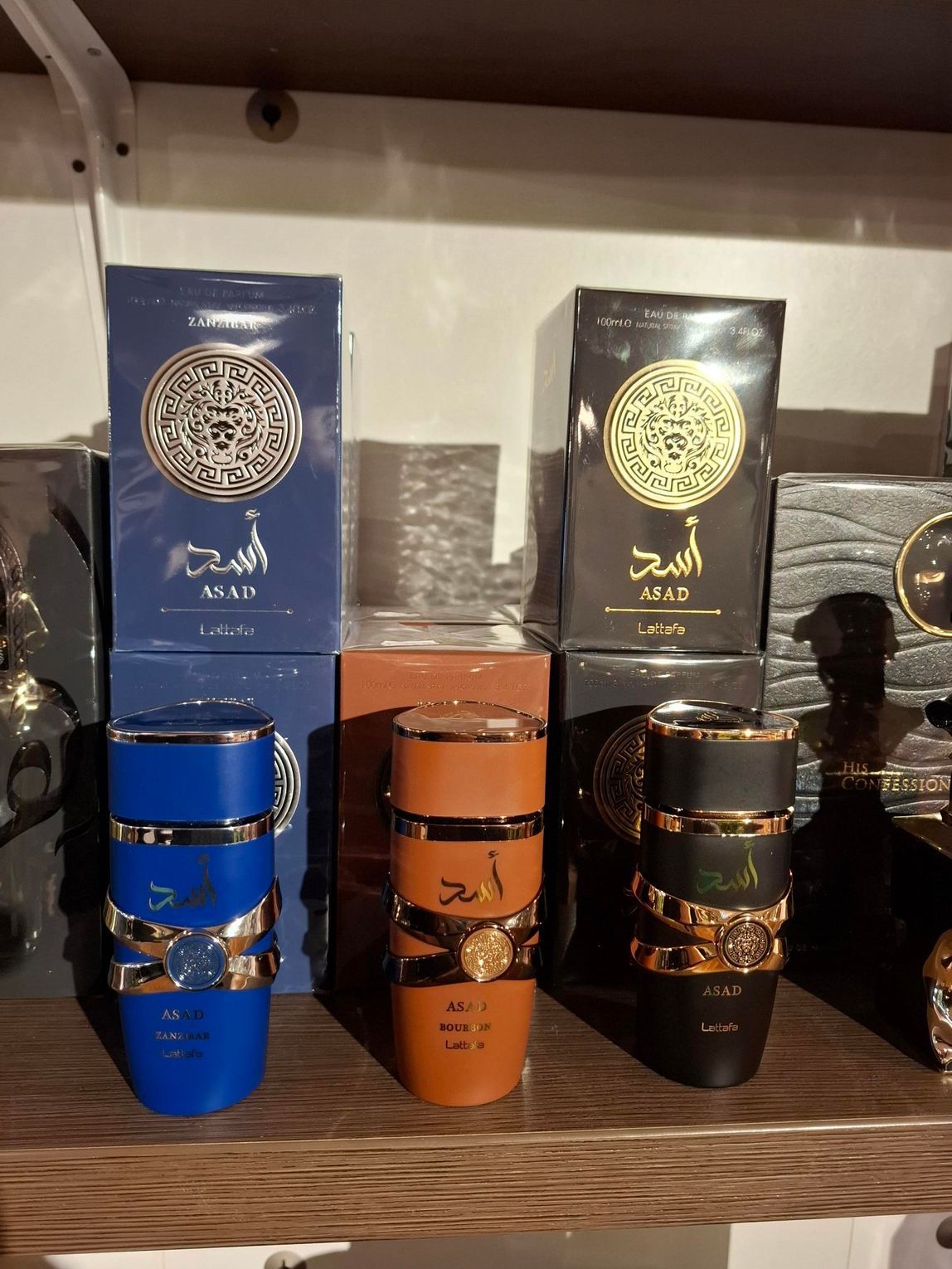 Parfumflesjes in roze, rood, wit en geel staan ​​uitgestald op een houten plank in een winkel.