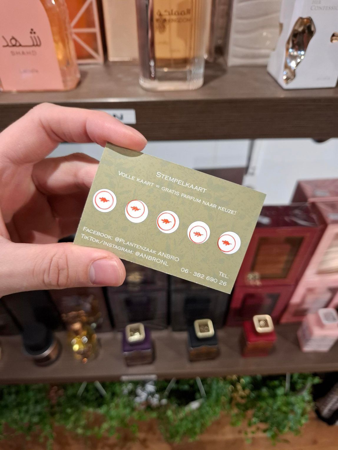 Een hand houdt een geel visitekaartje met bloemenmotief van 