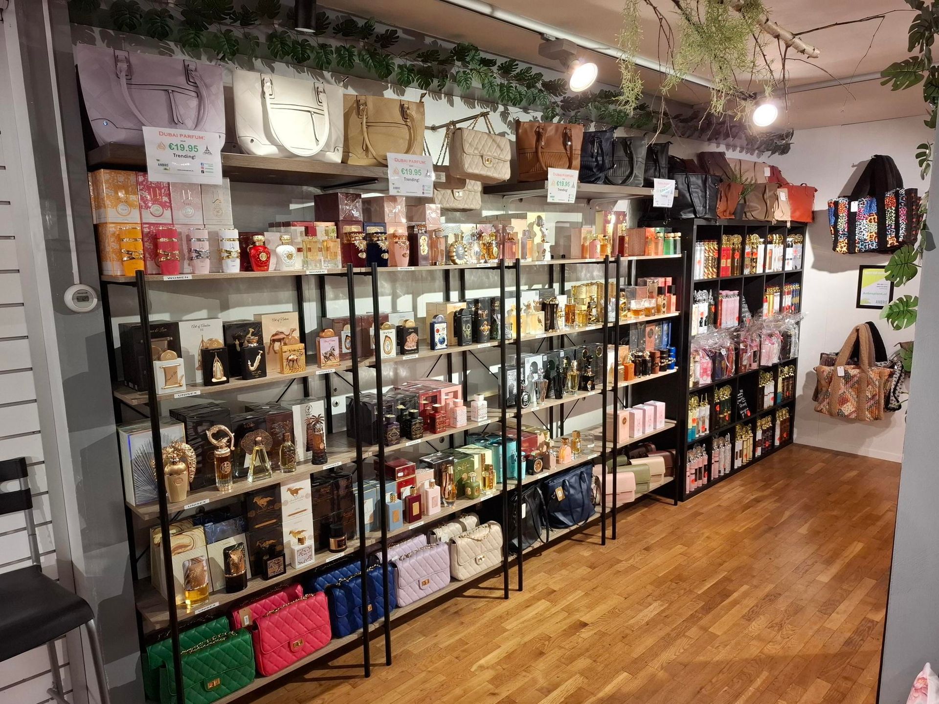 Een winkelgang met schappen vol diverse parfumdoosjes, glazen flesjes en handtassen.