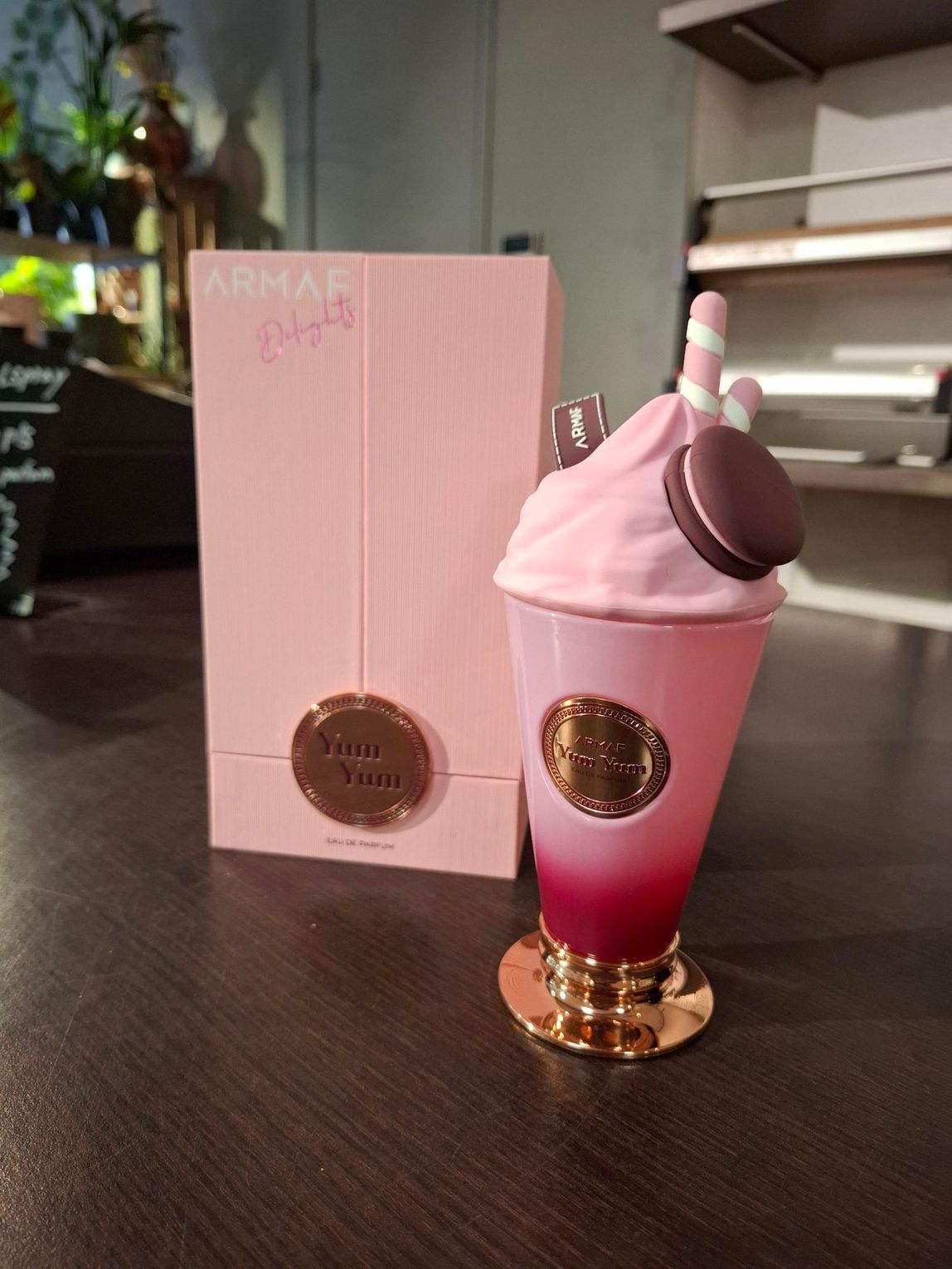 Het parfumflesje Armaf Signature Yum heeft de vorm van een roze milkshake met een macaron, en staat naast de bijpassende roze doos.