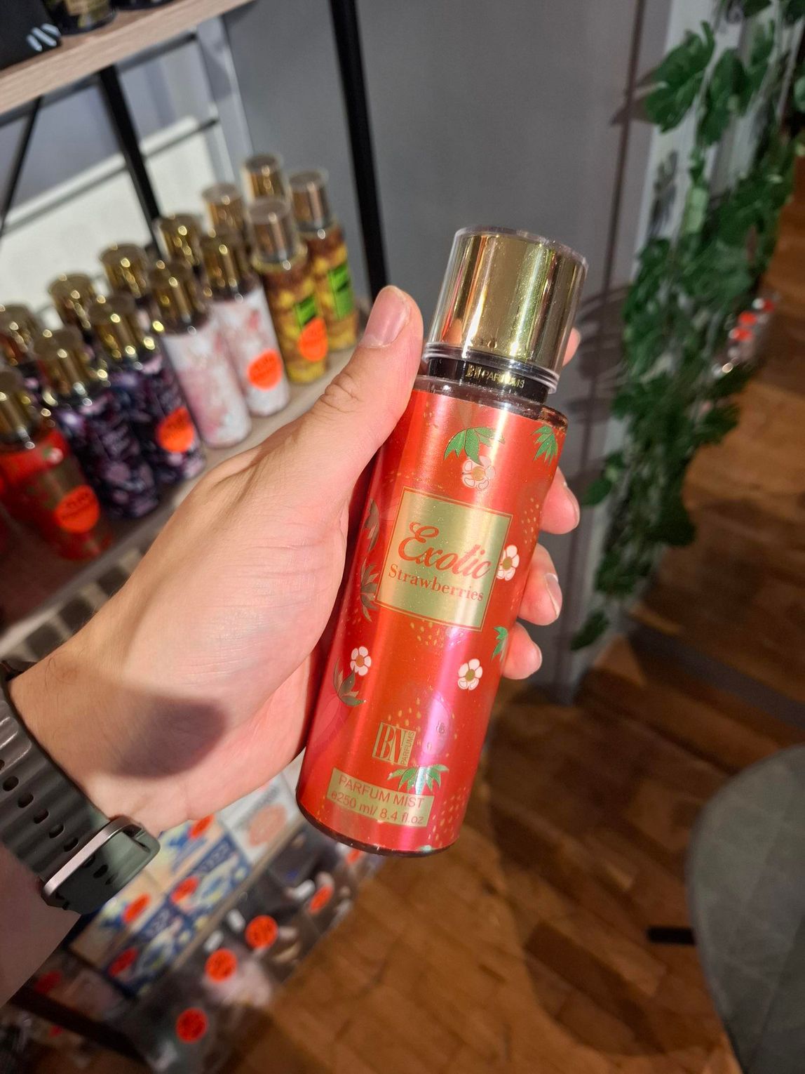 Een persoon houdt een rode fles Victoria's Secret 